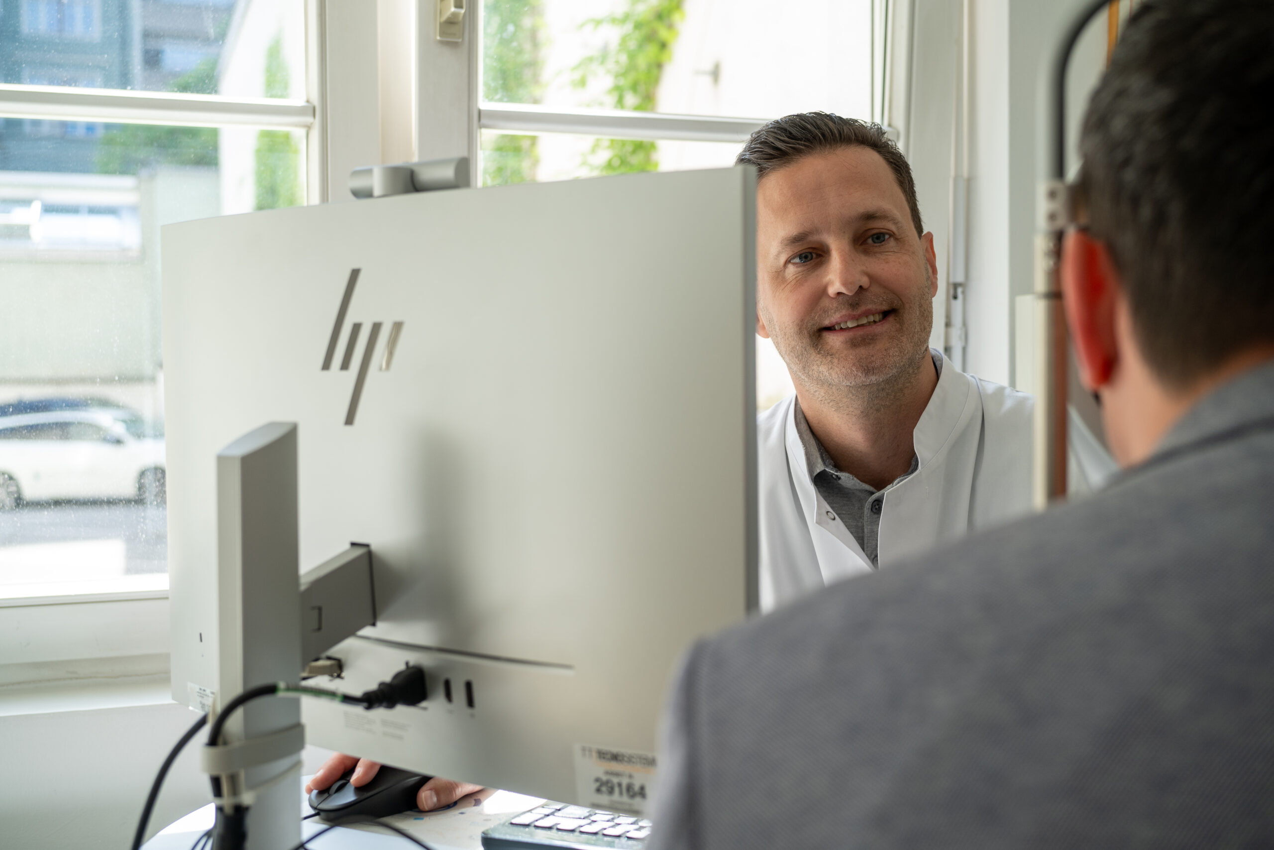 Prof. Dr. Mayer sitzt vor einem Computer und führt eine Untersuchung mit einem Patienten durch. Dabei kontrolliert er die Eignung für das Augenlasern